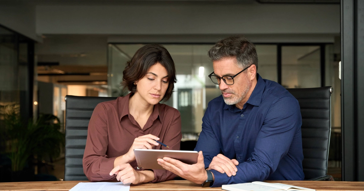 Two professionals review information on a tablet in a modern office while discussing Salesforce Implementation in Salt Lake City, UT.
